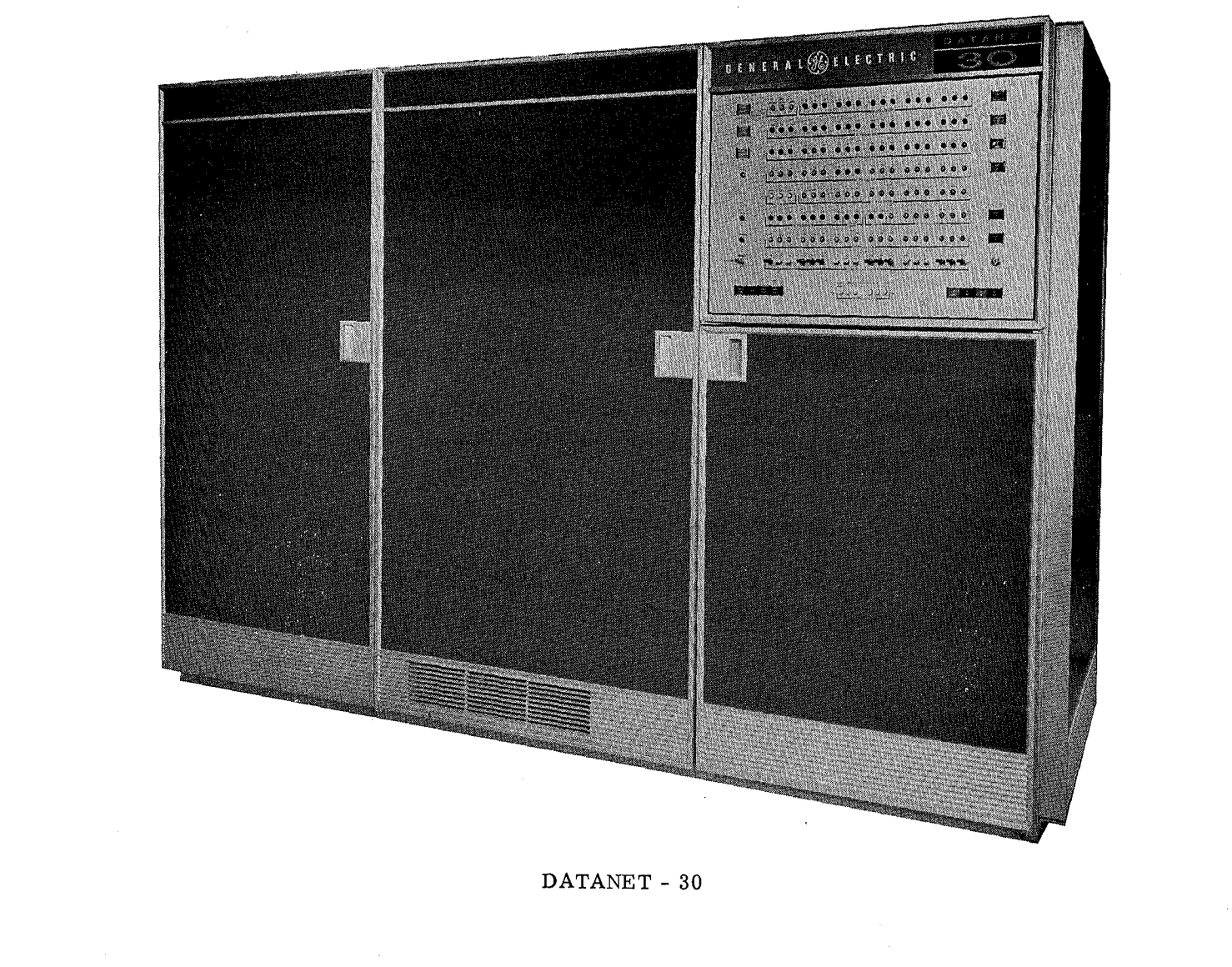 A black and white image of the General Electric Datanet-30. The
						computer resembles three refridgerators in size and form, with the
						right-most door being cut short by an access panel with indicator
						lights.