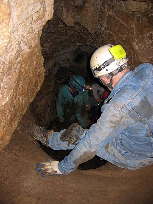 Photo from above of two cavers descending into a vertical pit