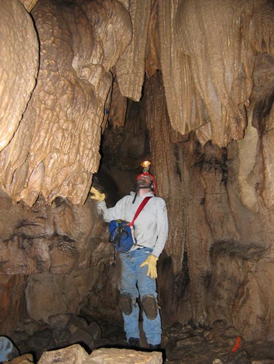 Photo of the author in a high-ceilinged cave room hung with
							stalactites