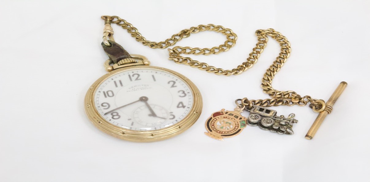 Gold pocket watch with train shaped charm.