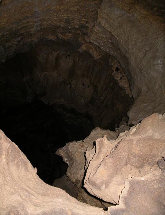 Photo showing the view from the tunnel entrance looking down into
							the cave shaft of the previous image