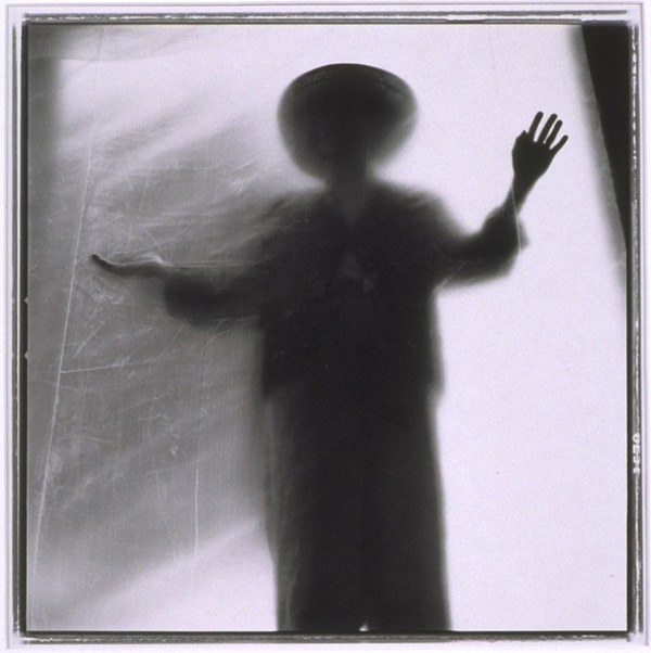 A person with outstretched arms silhouetted behind a cloth in black
                        and white